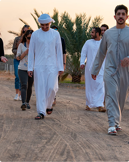 Emirati hosts walking with international guests at dusk